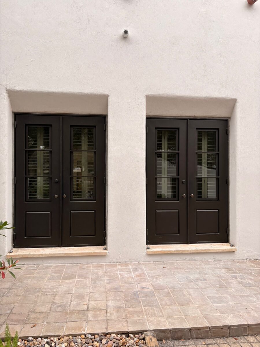 Full Exterior with Multiple Iron Doors — White Stucco Home